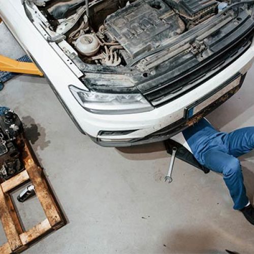 mechanic under car performing auto repair